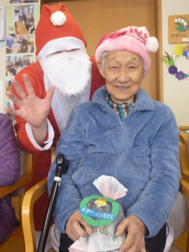 クリスマス衣装を着た高齢入居者とサンタクロース衣装の職員がイベントで写る